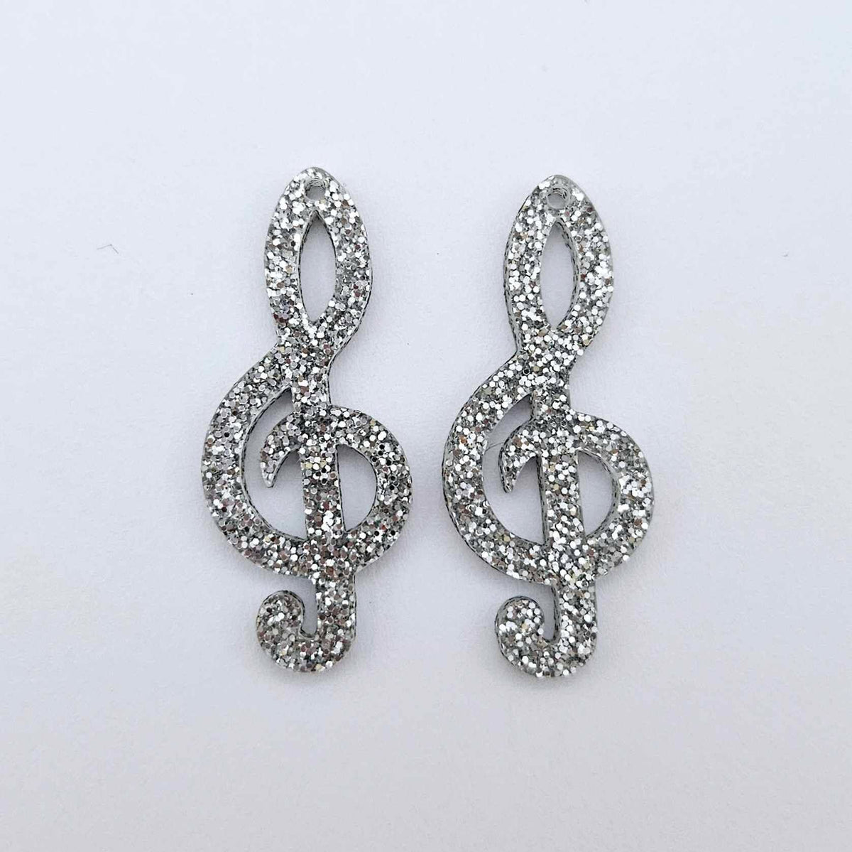 40mm silver glitter acrylic treble clef earring dangle blanks laid flat together.