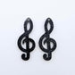 One pair of 40mm holographic black glitter acrylic treble clef earring dangle blanks laid flat.