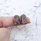 One pair of 15mm copper glitter acrylic boot stud earring blanks shown on a finger to for size reference.