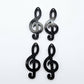 Two pairs of 40mm holographic black glitter acrylic treble clef earring dangle blanks laid flat.