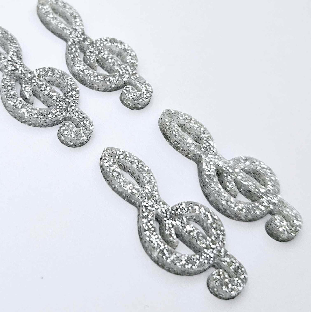 40mm silver glitter acrylic treble clef earring dangle blanks laid flat together.