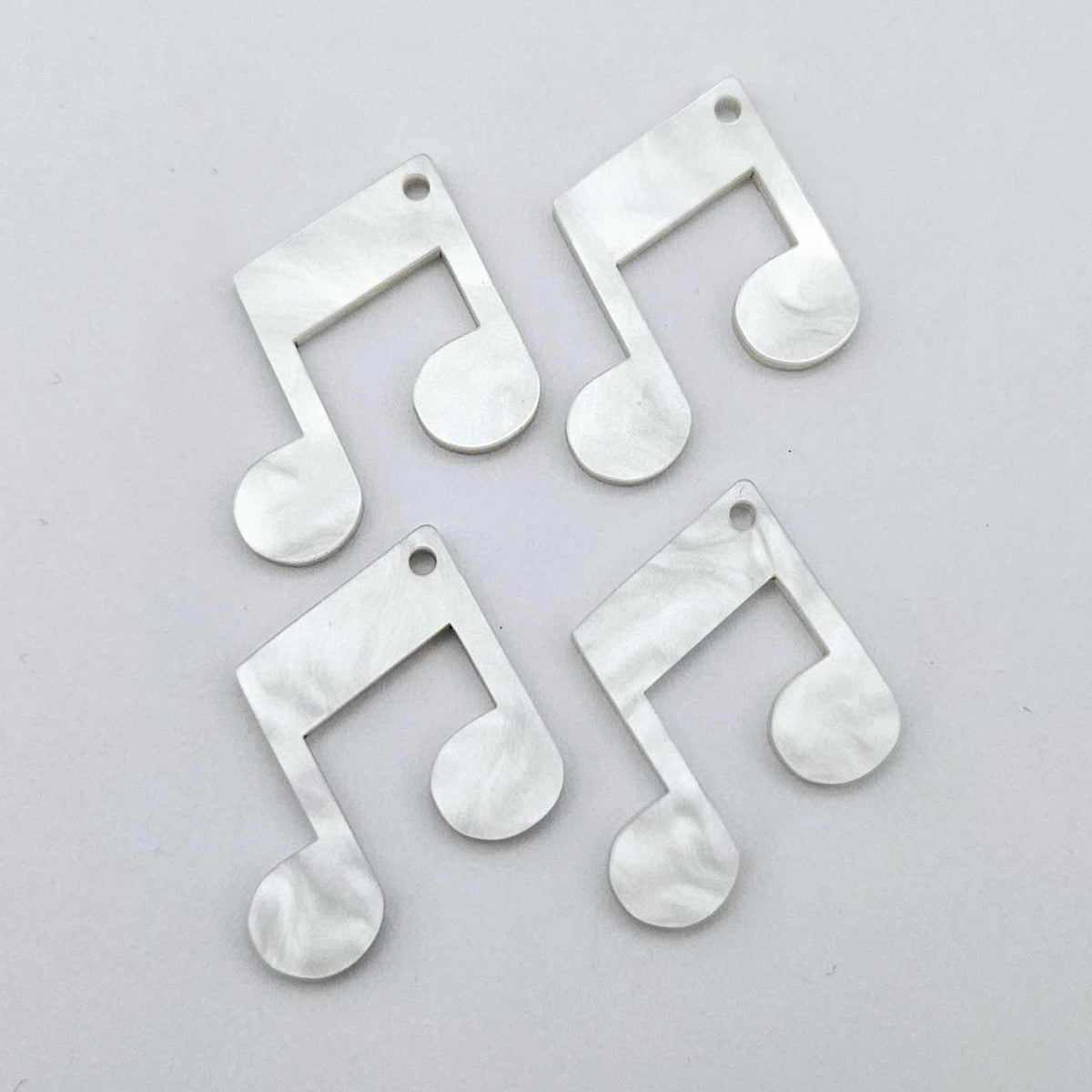 Two pairs of 35mm white marble acrylic music note earring dangle blanks laid flat together.