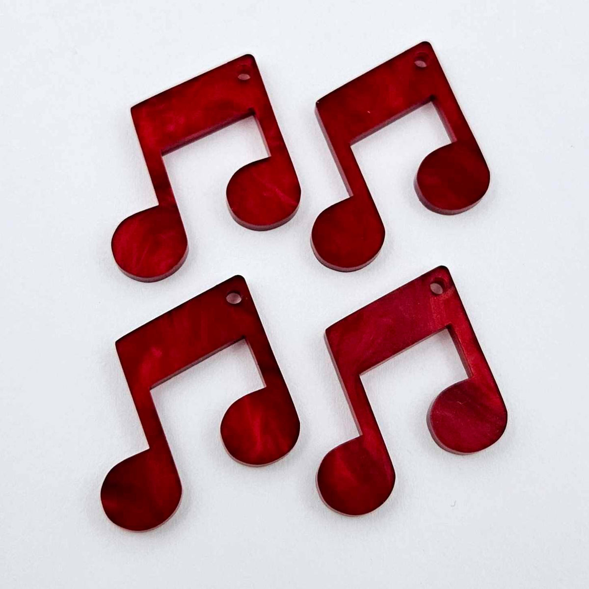 Two pairs of 35mm red marble acrylic music note earring dangle blanks laid flat together.