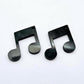 One pair of 35mm black marble acrylic music note earring dangle blanks laid flat together.
