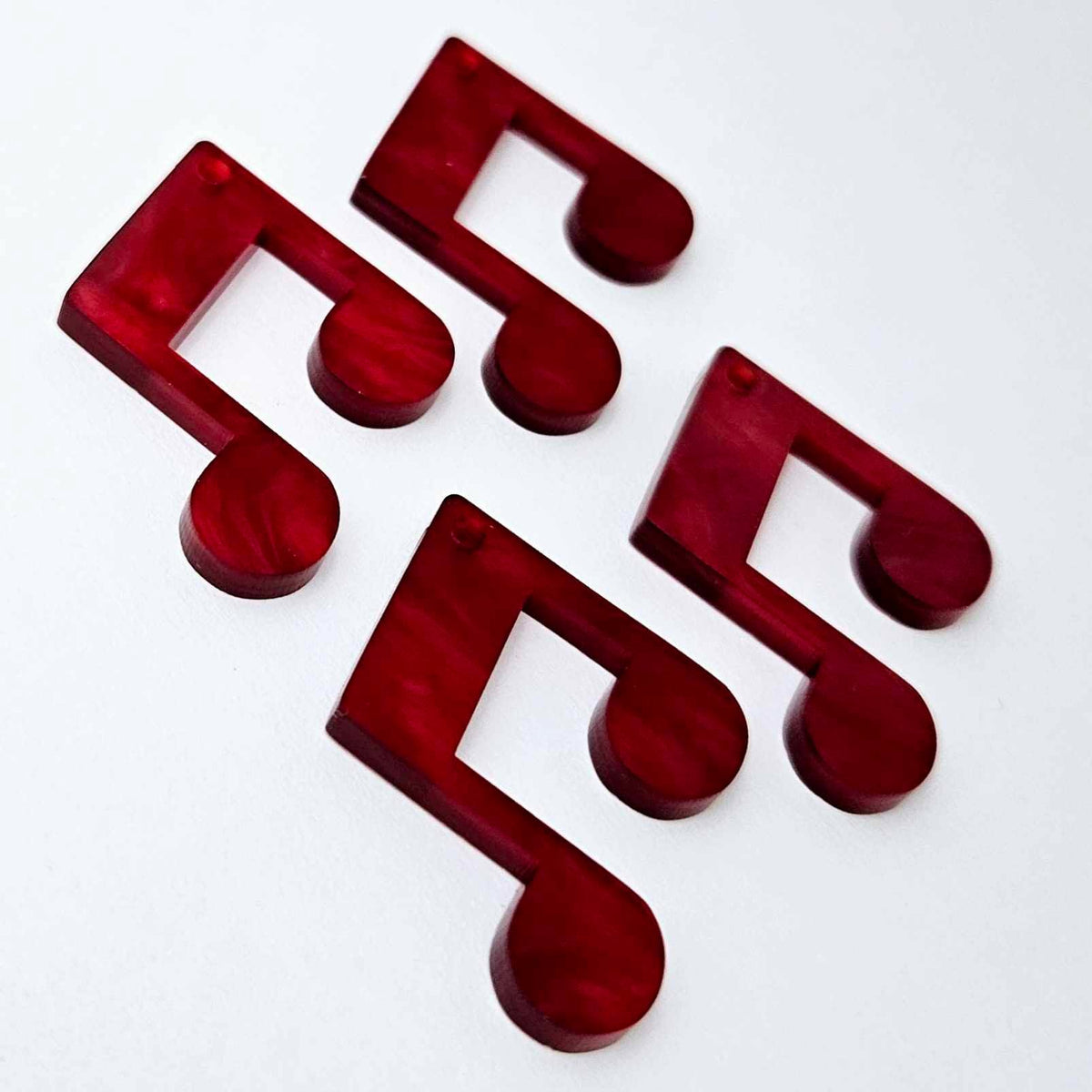 Two pairs of 35mm red marble acrylic music note earring dangle blanks laid flat together.