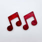 One pair of 35mm red marble acrylic music note earring dangle blanks laid flat together.