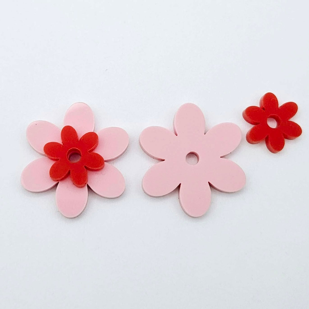 Two-piece solid acrylic flower earring blanks in Pastel Pink and Red, laid flat and designed for 20mm stainless steel hoops.