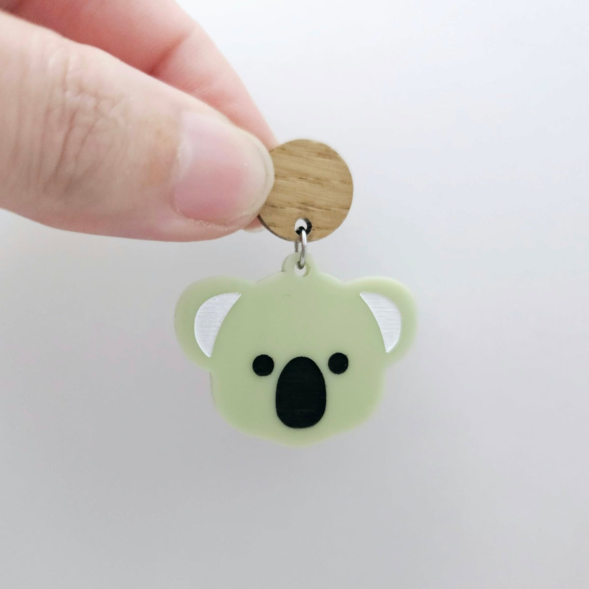 Solid eucalyptus green acrylic koala dangle earring blank assembled with a 14mm Oak wooden topper, featuring black paint-filled eyes and nose with white inner ears, showing how the pieces can be combined to create a finished koala earring.