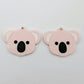 Pair of solid strawberry milkshake acrylic koala dangle blanks laid flat, featuring engraved eyes, nose and inner ear details paint filled with black and white for a cute Australiana earring design.