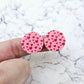 One pair of 20mm Pink & Red Hearts UV printed acrylic stud earring blanks displayed on a finger to show their size, perfect for creating fun statement stud earrings.