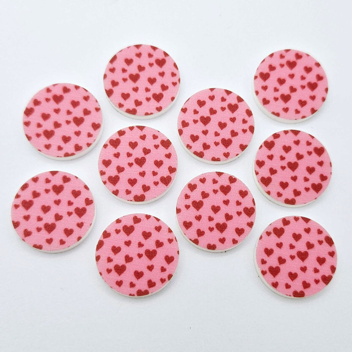Five pairs of 20mm Pink & Red Hearts UV printed acrylic circle stud earring blanks laid flat, featuring a pink background with little red hearts scattered throughout.