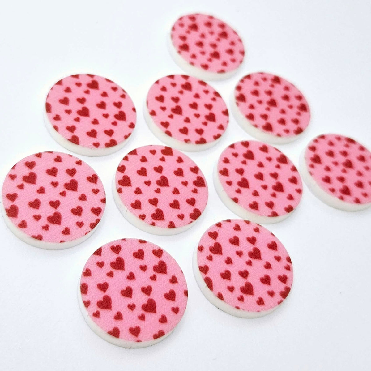 Five pairs of 20mm Pink & Red Hearts UV printed acrylic circle stud earring blanks laid flat, featuring a pink background with little red hearts scattered throughout.